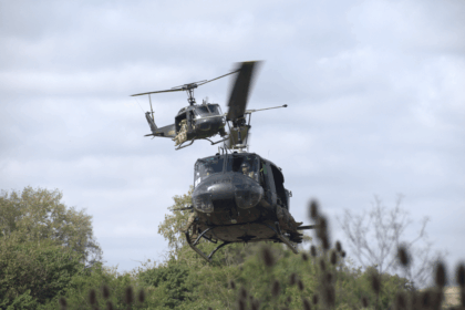 Helicóptero UH-1H matrícula AE-471 de la Aviación de Ejército Argentino en vuelo rasante con tropas a bordo, acompañado por un segundo Huey en formación.