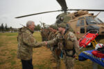 Autoridad de gobierno saluda a efectivos de rescate del Ejército de Chile frente a un helicóptero de transporte durante el despliegue militar por el sistema frontal.