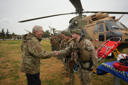 Autoridad de gobierno saluda a efectivos de rescate del Ejército de Chile frente a un helicóptero de transporte durante el despliegue militar por el sistema frontal.