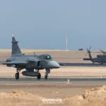 Gripen E 4106 de la Fuerza Aérea Brasileña en pista con un Black Hawk al fondo