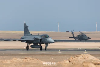 Gripen E 4106 de la Fuerza Aérea Brasileña en pista con un Black Hawk al fondo