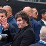 Javier Milei saluda con la mano rodeado de custodia y fotógrafos en un acto público