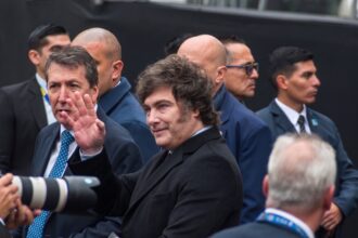 Javier Milei saluda con la mano rodeado de custodia y fotógrafos en un acto público