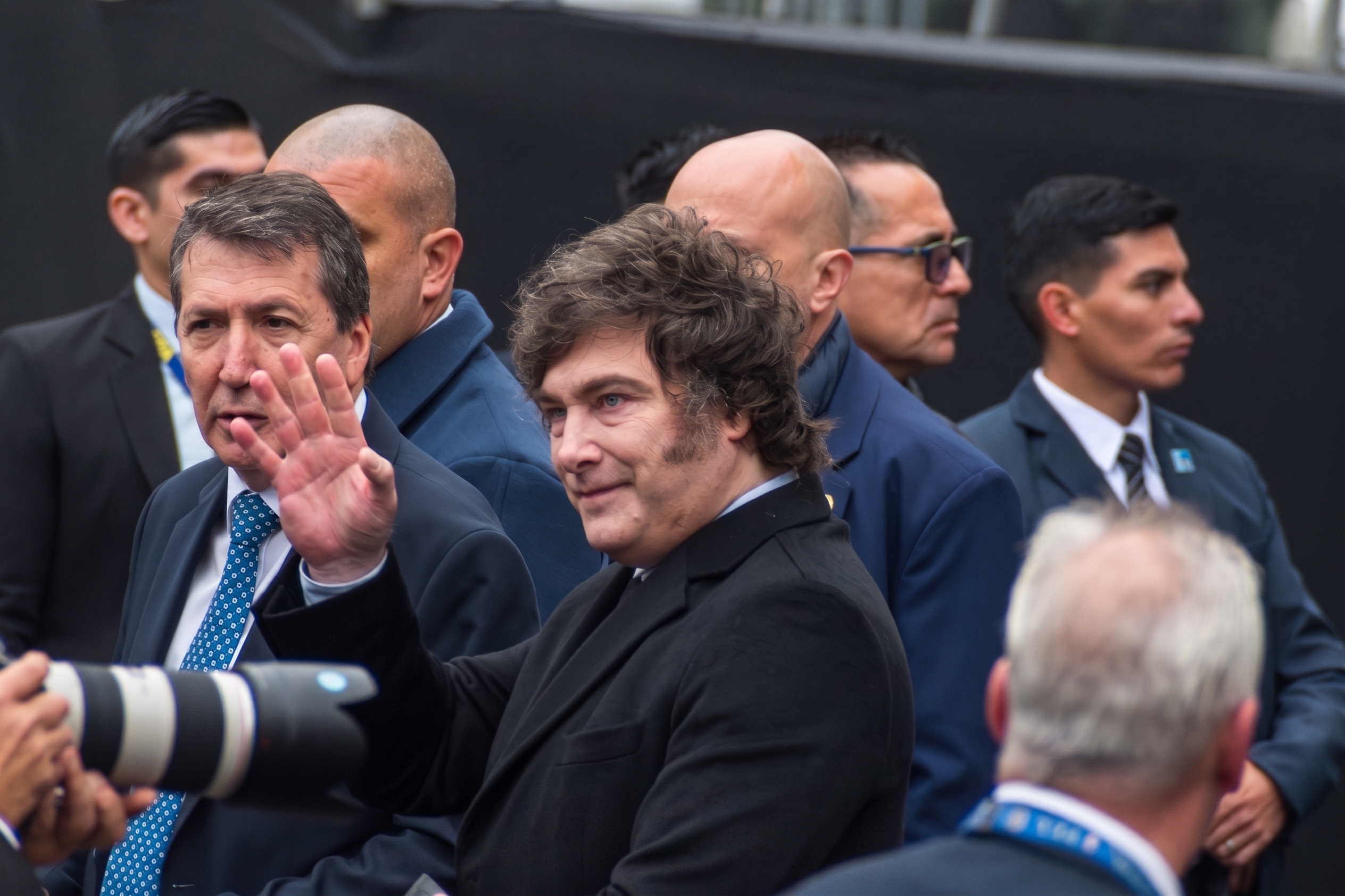 Javier Milei saluda con la mano rodeado de custodia y fotógrafos en un acto público
