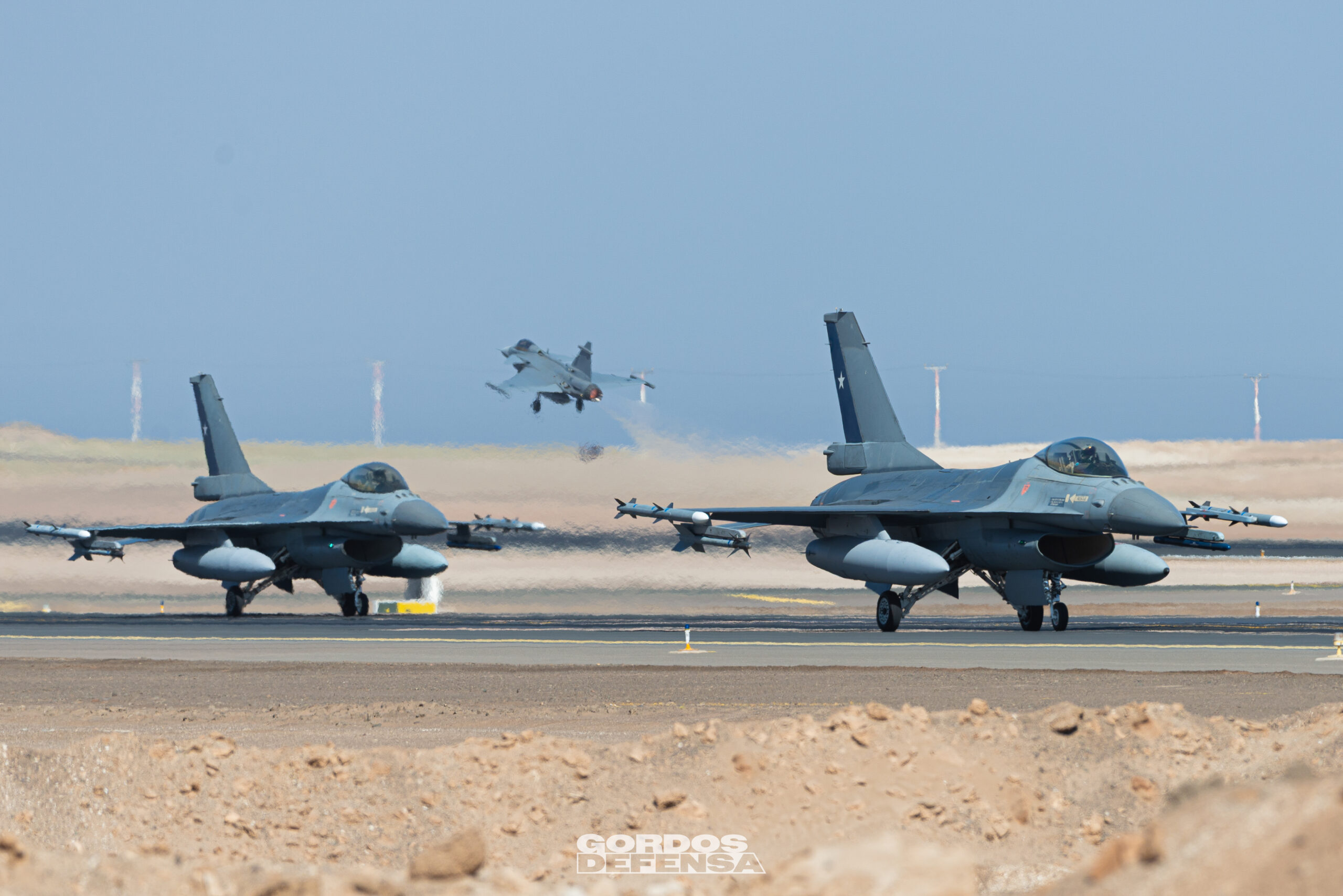 Dos F-16 de la Fuerza Aérea de Chile en pista mientras un Gripen despega al fondo