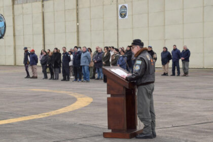 Oficial de la Aviación Naval argentina lee el anuncio del Plan Dédalo ante el personal formado frente a un hangar.