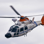 Helicóptero AS365 Dauphin matrícula PA-43 de la aviación de Prefectura Naval en vuelo, con torreta electroóptica sobre la cabina y fenestrón naranja de alta visibilidad.