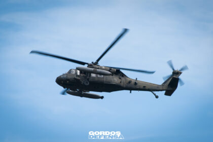 Helicóptero UH-60 Black Hawk utilitario en vuelo de perfil contra cielo azul, con tanques de combustible externos