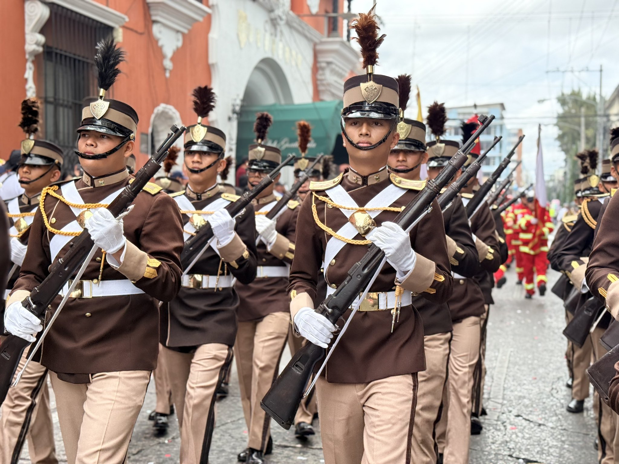 Cadetes de la Escuela de Comunicaciones y Electrónica de Guatemala marchan con uniforme de gala café y fusiles