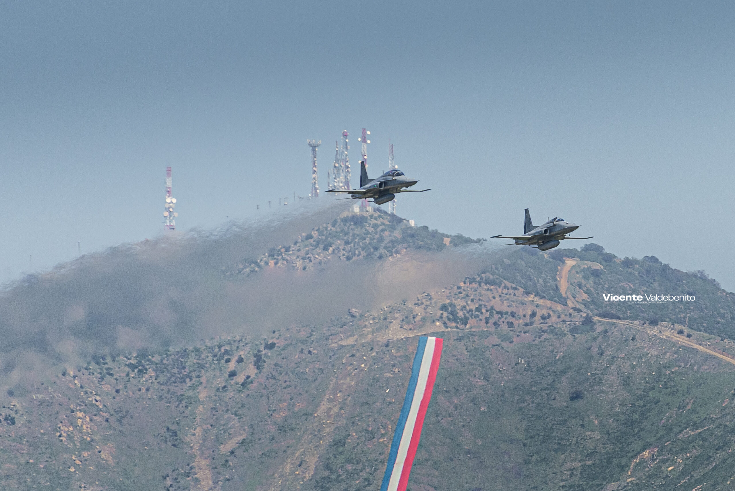 Dos cazas F-5 Tigre III de la Fuerza Aérea de Chile en vuelo bajo frente a un cerro con antenas (91)