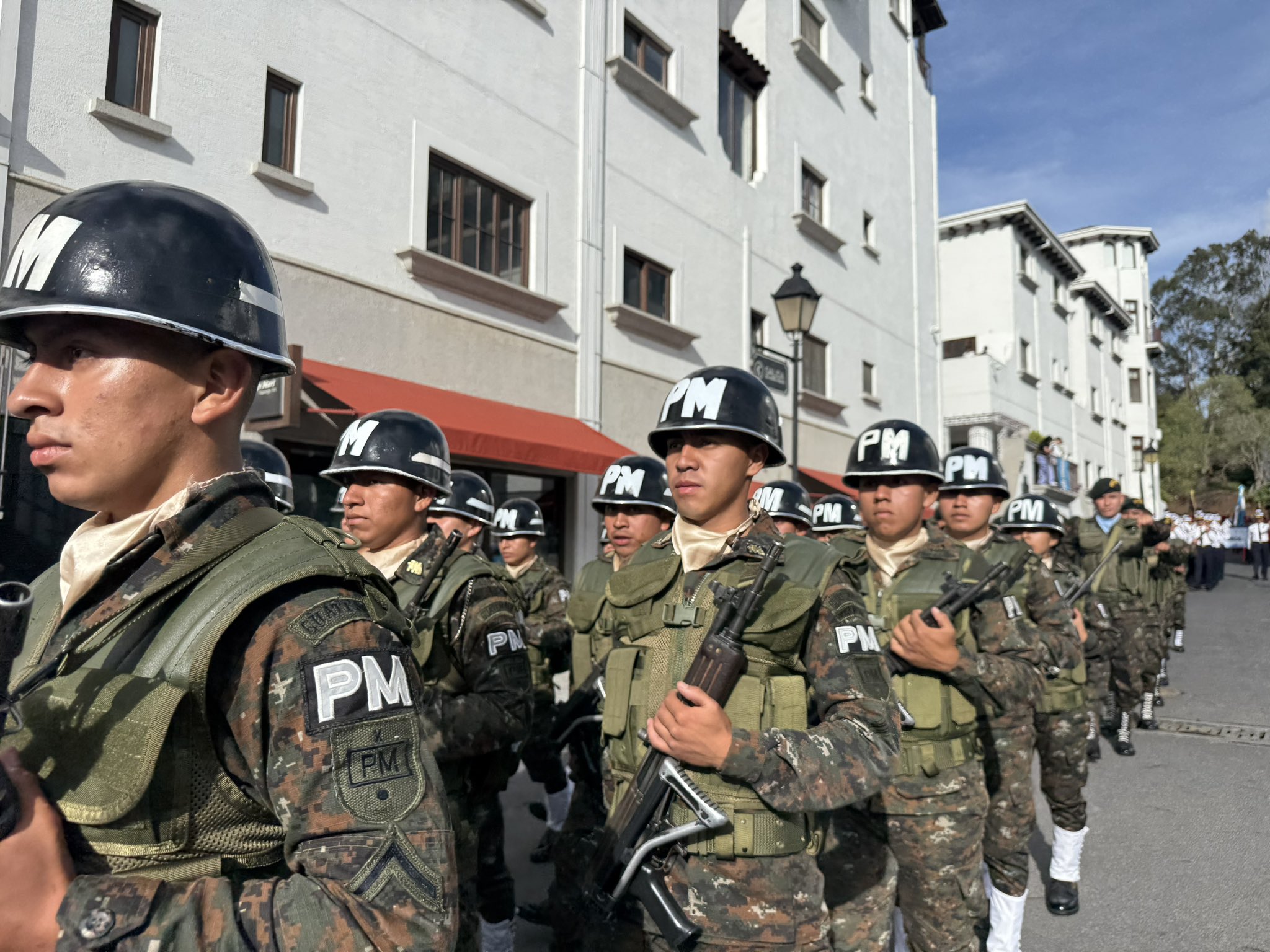 Efectivos de la Policía Militar de Guatemala con casco negro PM y fusiles marchan en el desfile de Independencia