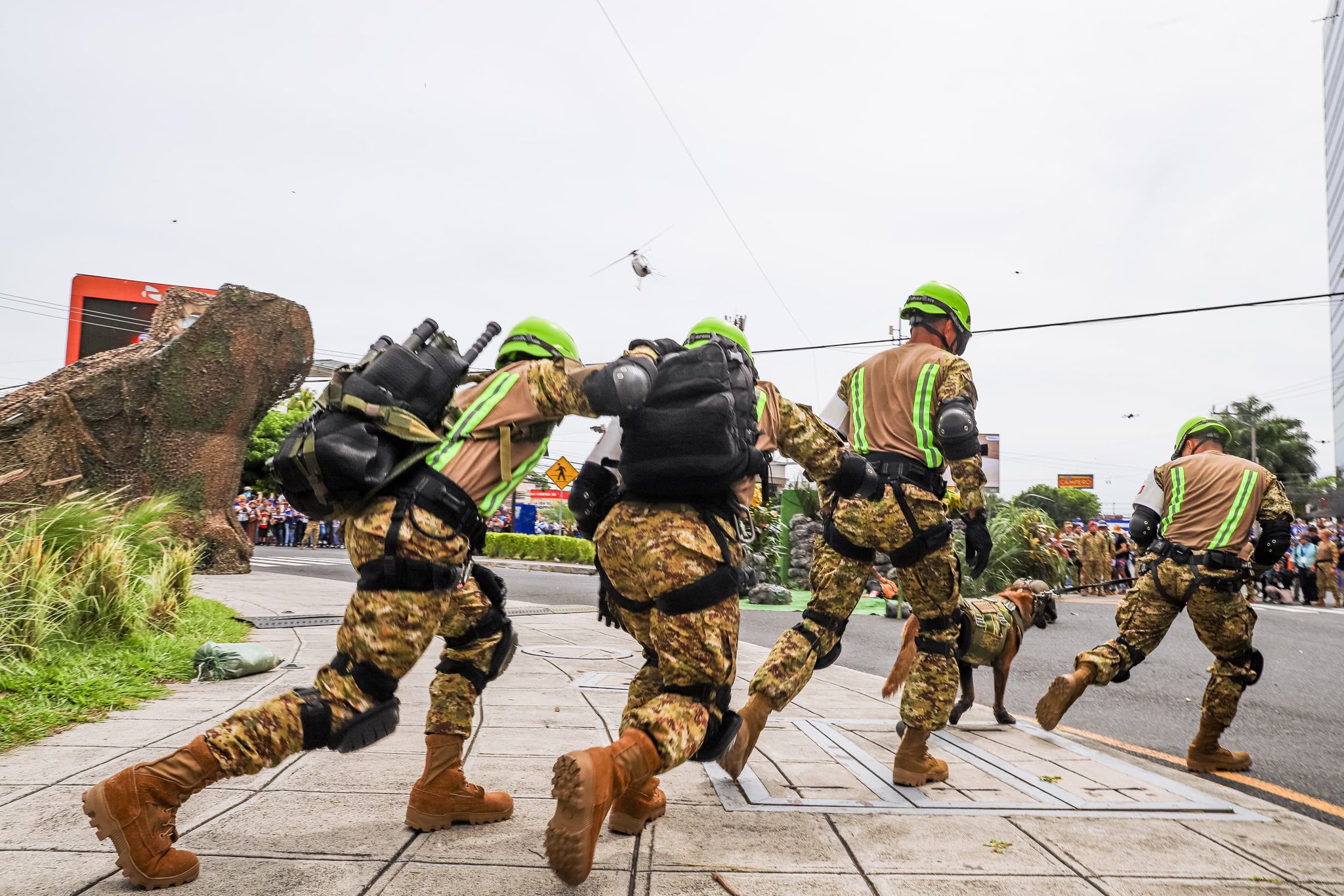Rescatistas de la Fuerza Armada de El Salvador corren con un perro K9 durante el desfile del 15 de septiembre en San Salvador