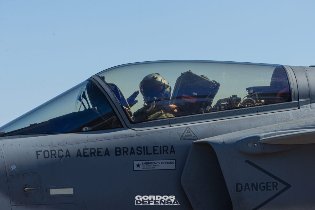 Piloto con casco saludando desde la cabina de un Gripen de la Força Aérea Brasileira